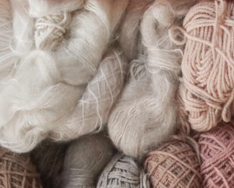 close up of different yarn skeins in white beige and pink