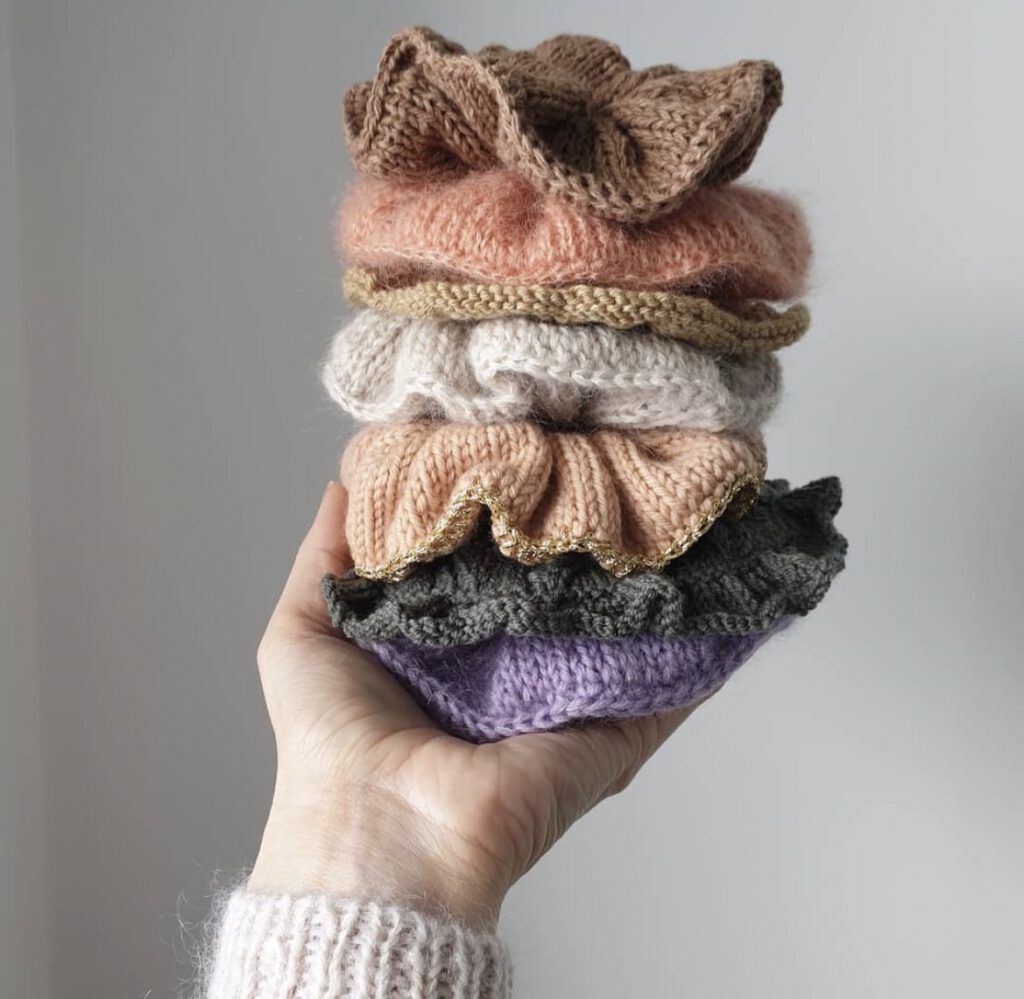 A hand holding scrunchies of different colours.