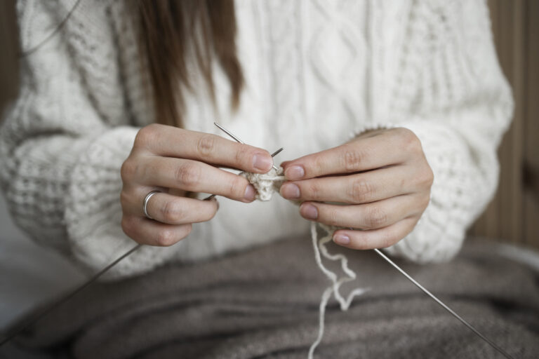 close up of woman knitting at home