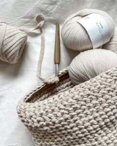 crochet hook, beige yarn and crochet project