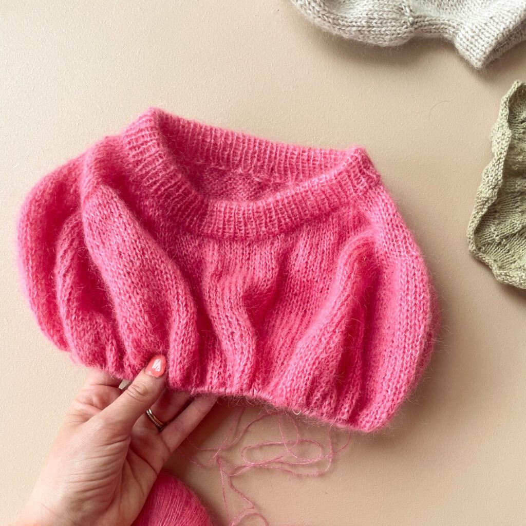 close up of pink knitting project with female hand