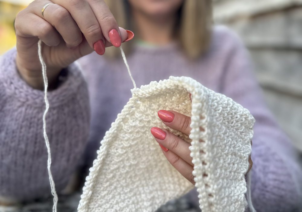 Woman unraveling knitting project